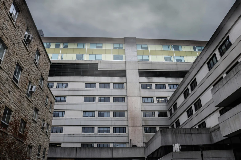 a very tall building sitting in the middle of a city, a photo, unsplash, brutalism, hospital ward, big overcast, brown, cornell