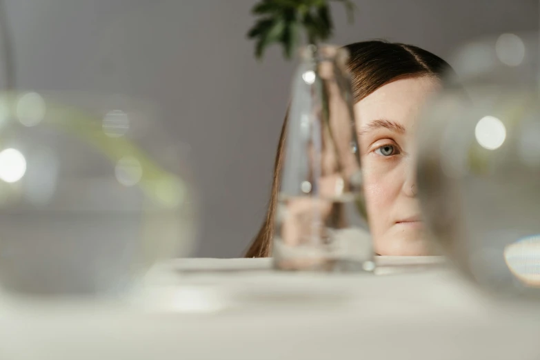 a woman sitting at a table with a flower in a vase, pexels contest winner, hyperrealism, blank expression on her face, at a dinner table, girl with white eyes, close-up photo