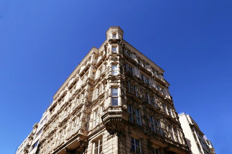 a tall building sitting on the side of a street, a photo, unsplash, art nouveau, clear blue sky, high details photo, artsationhq, brown