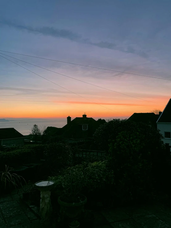 a view of the sunset from the roof of a house, by Matthew Smith, looking out over the sea, profile image, taken from the high street, taken in the early 2020s