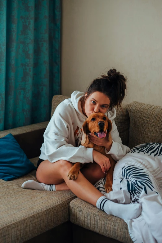 a woman sitting on a couch holding a dog, pexels contest winner, hotel room, woman in streetwear, brown haired, australian