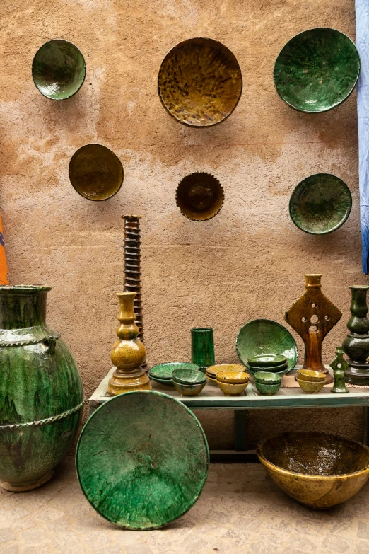 a group of green vases sitting on top of a table, a still life, inspired by Riad Beyrouti, trending on unsplash, cloisonnism, shelves full of medieval goods, rusty colors, colorful signs, metallic polished surfaces