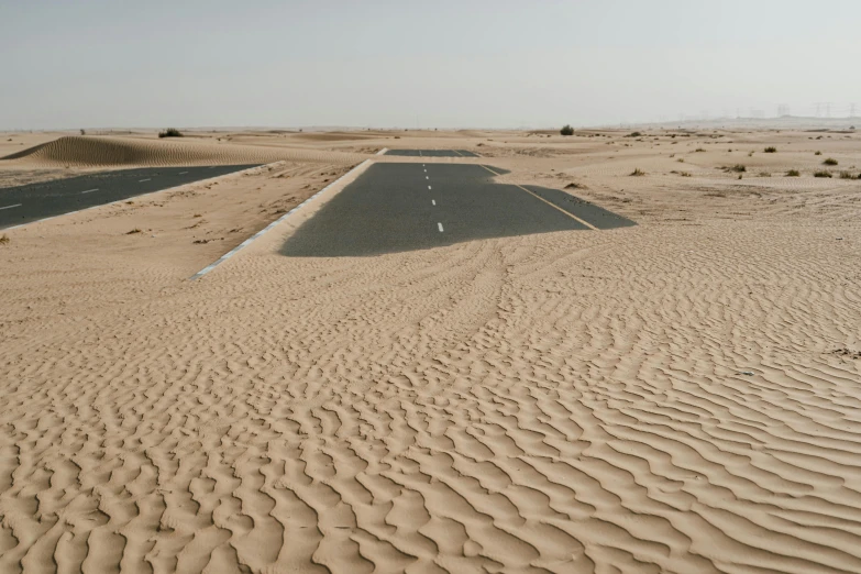 an empty road in the middle of a desert, pexels contest winner, les nabis, half submerged in heavy sand, gta : dubai, 3 / 4 wide shot, runway