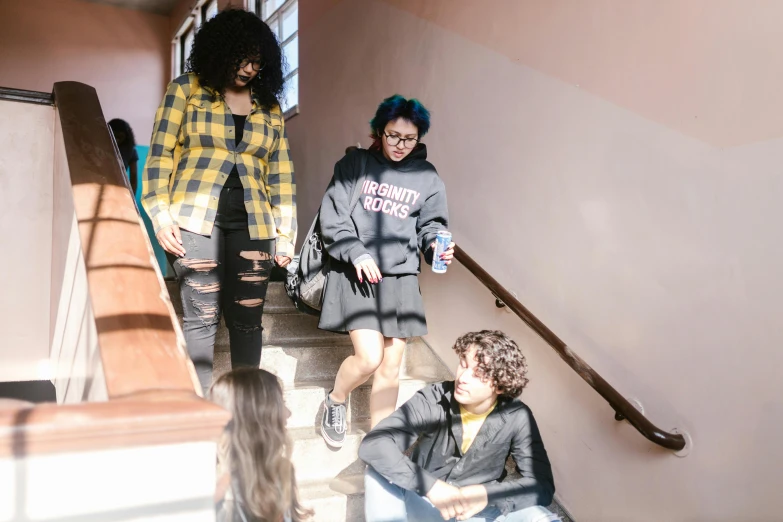 a group of people walking down a flight of stairs, by Nina Hamnett, trending on pexels, happening, tall female emo art student, sitting down, academic clothing, 15081959 21121991 01012000 4k