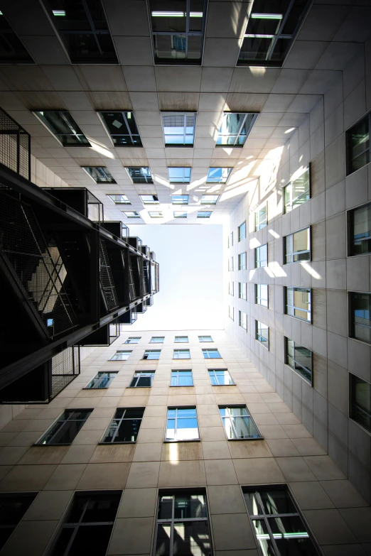 a very tall building with lots of windows, inspired by Richard Wilson, unsplash, cube portals, view from ground, narrow, a wide open courtyard in an epic