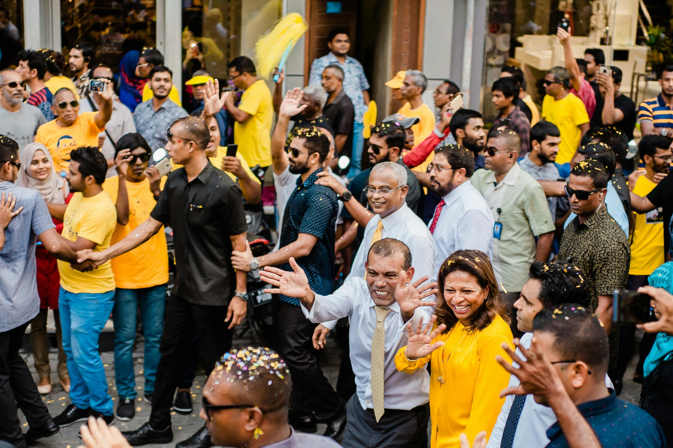 a group of people that are standing in the street, pexels contest winner, hurufiyya, the king in yellow, exiting store, colombo sri lankan city street, cheering crowds