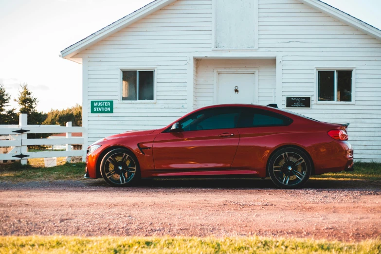 a red sports car parked in front of a white house, by Tom Bonson, pexels contest winner, bmw, next to a red barn, profile image, brown