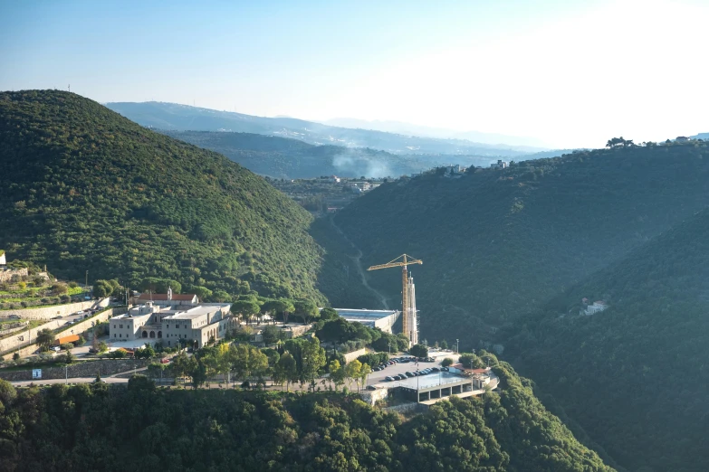 a large building sitting on top of a lush green hillside, pexels contest winner, les nabis, under construction, overlooking a valley with trees, calatrava, holy grail