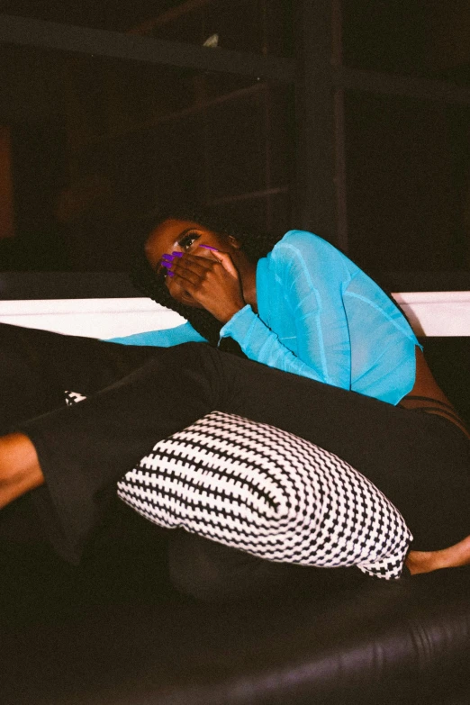 a man laying on top of a black couch, an album cover, by Dulah Marie Evans, trending on pexels, woman in streetwear, black light, pouting, ☁🌪🌙👩🏾