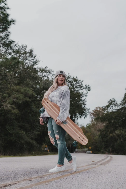 a woman walking down a street holding a skateboard, unsplash contest winner, standing on a forest, young southern woman, gray skies, holding wood saw