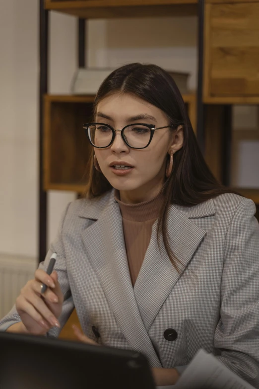 a woman sitting in front of a laptop computer, trending on pexels, academic art, wearing a suit and glasses, pokimane, interview, фото девушка курит