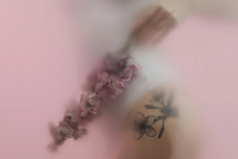 a close up of a flower with a blurry background, a tattoo, by Emma Andijewska, trending on pexels, pink background, floating in perfume, arms covered in gang tattoo, orchid