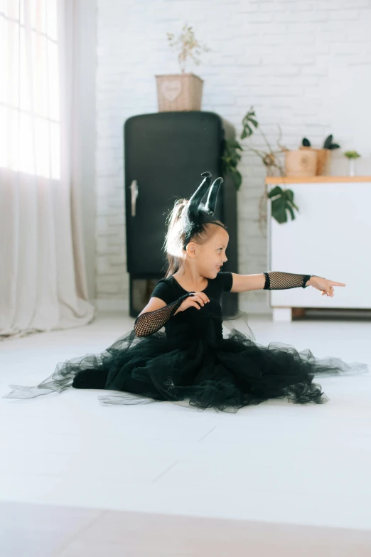 a little girl in a black dress sitting on the floor, spell casting wizard, twirling, wearing black witch hat, premium