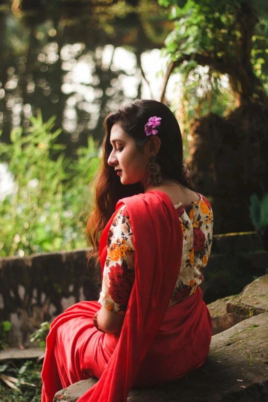 a woman sitting on a bench with a flower in her hair, a portrait, inspired by Sunil Das, pexels contest winner, wearing a blouse, red silk flowing fabric, showing her shoulder from back, profile image