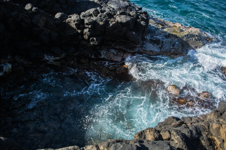 a man standing on top of a rocky cliff next to the ocean, whirlpool, deep sinkhole, white lava, top - down photograph