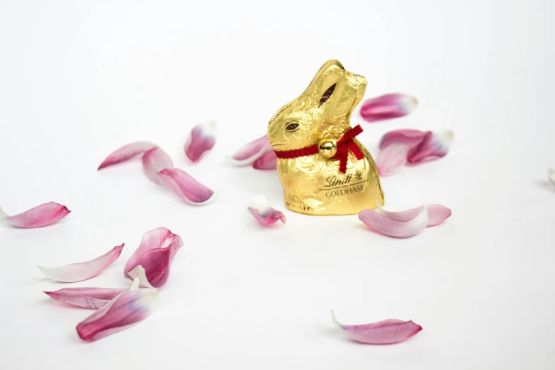 a chocolate bunny sitting on top of a pile of petals, inspired by Jeff Koons, art nouveau, unrefined sparkling gold nugget, official product photo, view from the side, lipstick