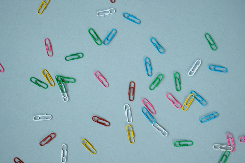 a bunch of paper clips sitting on top of a table, colored dots, floating away, high quality product image”, intriguing details