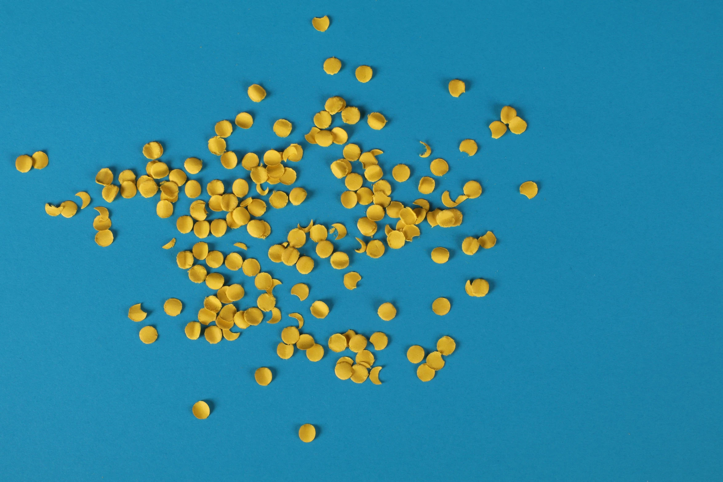 a pile of yellow seeds sitting on top of a blue surface, pexels, computer art, fairy circles, background image, abstract claymation, gold plated