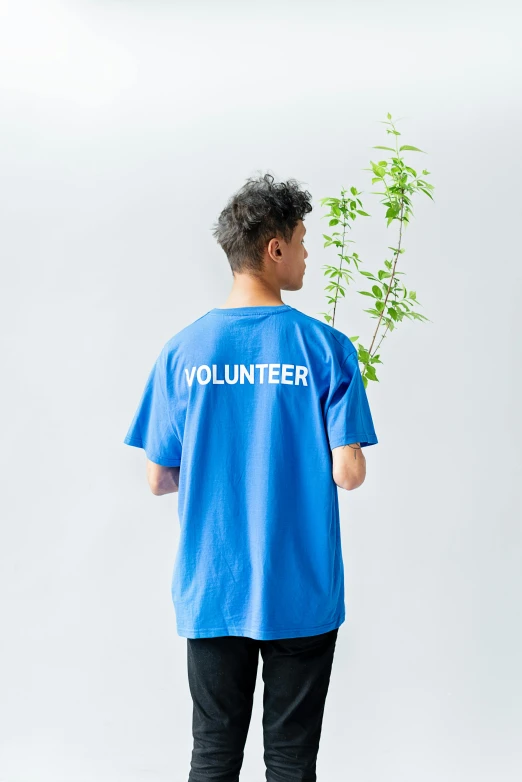 a man holding a plant and wearing a volunteer t - shirt, by Miyamoto, neon blue color, 165 cm tall, cleanest image, home