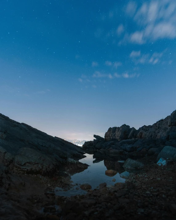 a body of water sitting on top of a rocky hillside, by Sebastian Spreng, sky night, high-quality photo, pov photo