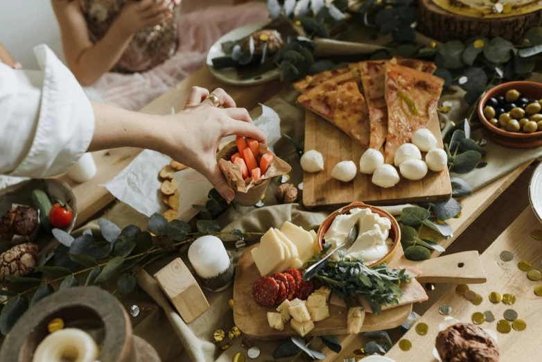 a group of people sitting around a table filled with food, a still life, by Julia Pishtar, pexels contest winner, renaissance, lots of mozzarella balls, holiday vibe, on a wooden tray, full-body