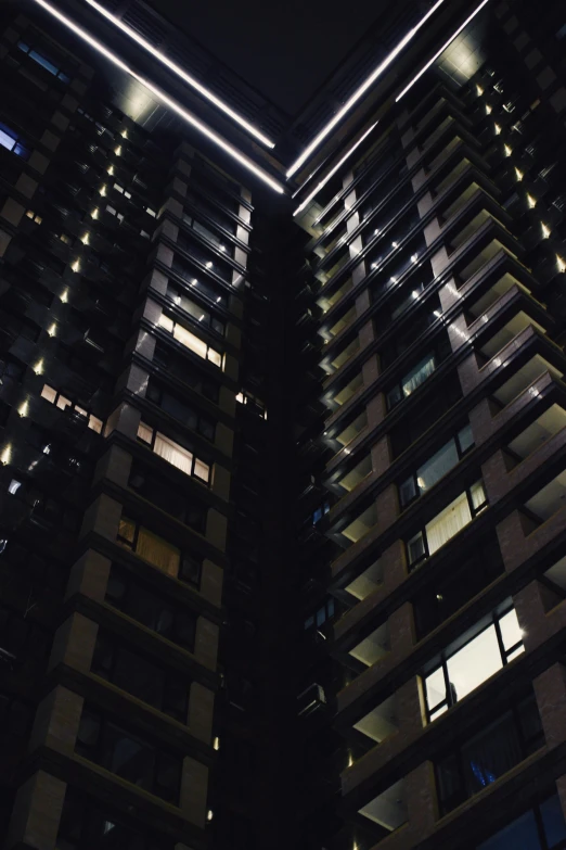 a tall building is lit up at night, inspired by Cheng Jiasui, unsplash, brutalism, low angle!!!!, my home, nighttime!!, low quality photo