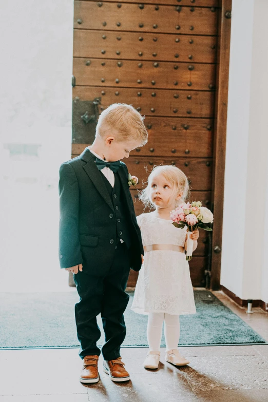 a couple of young children standing next to each other, pexels contest winner, happening, formal wear, in church, delightful surroundings, a blond