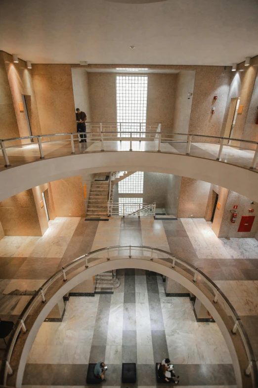 a couple of people that are inside of a building, large staircase, tiled room squared waterway, alvaro siza, set in bank vault room