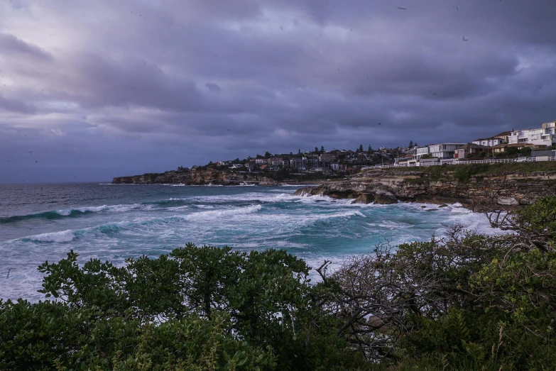 a view of the ocean from the top of a hill, pexels contest winner, australian tonalism, bondi beach in the background, storm in the evening, trees and cliffs, album