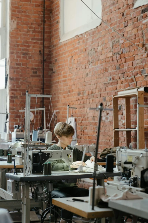 a group of people working on sewing machines, by Nina Hamnett, brick building, girl in studio, ignant, wide