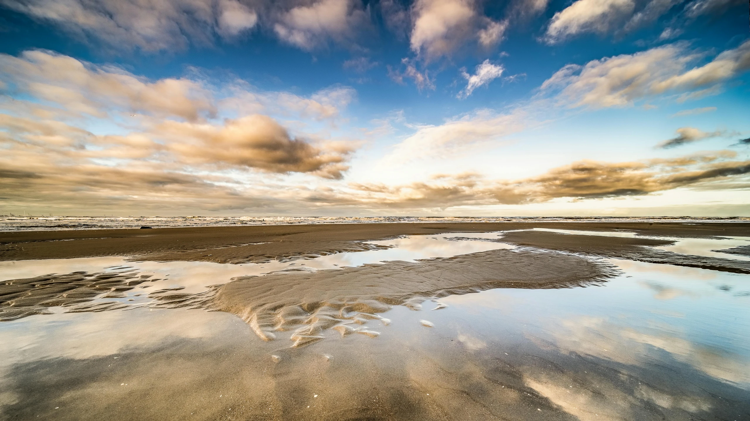 a large body of water sitting on top of a sandy beach, by Daniel Seghers, unsplash contest winner, marvellous reflection of the sky, swirling clouds, today\'s featured photograph 4k, wet puddles reflecting