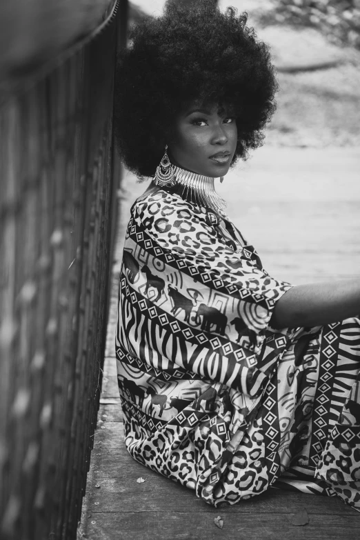 a black and white photo of a woman with an afro, unsplash, patterned clothing, sza, leaning on door, on beach