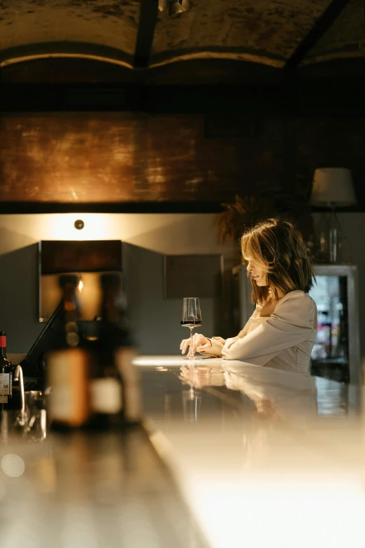 a woman sitting at a bar with a glass of wine, calm lighting, tending on arstation, pristine and clean, uplit