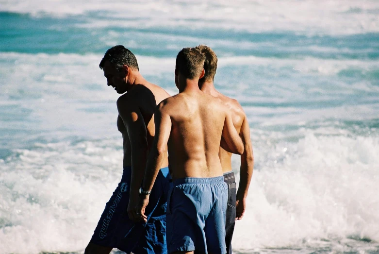 a couple of men standing on top of a beach next to the ocean, sweaty wet skin, group of people, profile image, boys