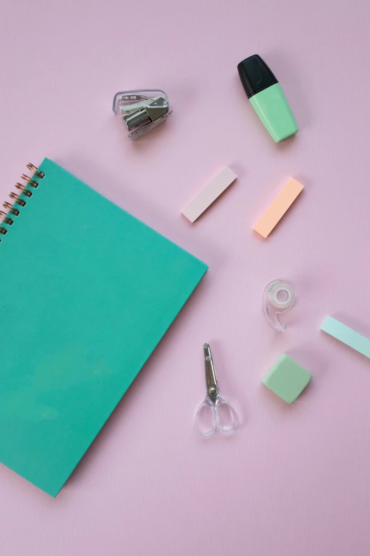 a green notebook surrounded by office supplies on a pink surface, trending on pexels, turquoise color scheme, 15081959 21121991 01012000 4k, pastel makeup, blue and purple colour scheme