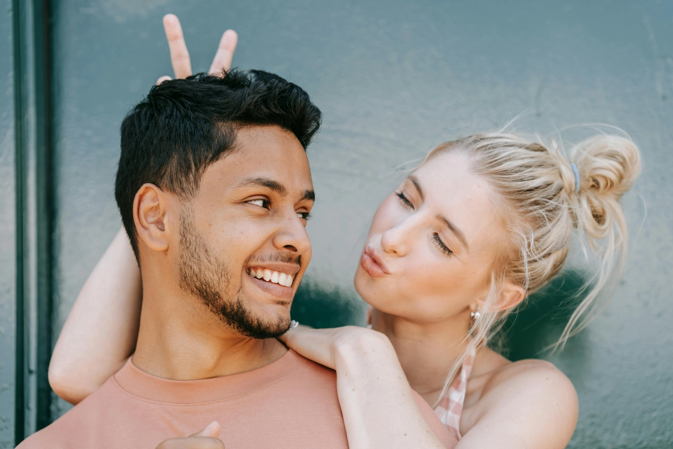 a man and a woman standing next to each other, trending on pexels, lean man with light tan skin, peace and love, spiky, playful