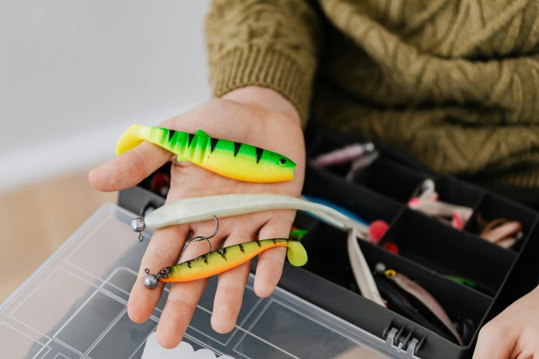 a person holding several fishing lures in their hands, by Julia Pishtar, trending on pexels, plasticien, rectangle, spanners, fluorescent, realistic »