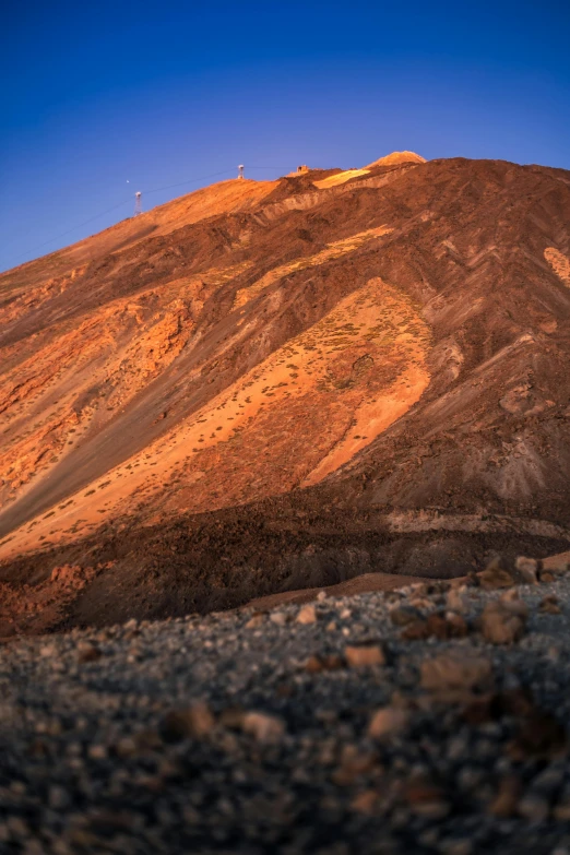 a mountain covered in dirt and rocks under a blue sky, by Julia Pishtar, epic red - orange sunlight, exterior shot, chocolate, brown