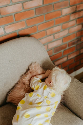 a baby sleeping on a couch with a teddy bear, unsplash, brick walls, low quality photo, bird view, cozy arm chairs