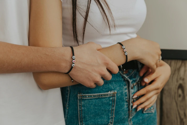 a man and a woman standing next to each other, trending on pexels, bracelets, black and silver, sisters, wearing a dark shirt and jeans
