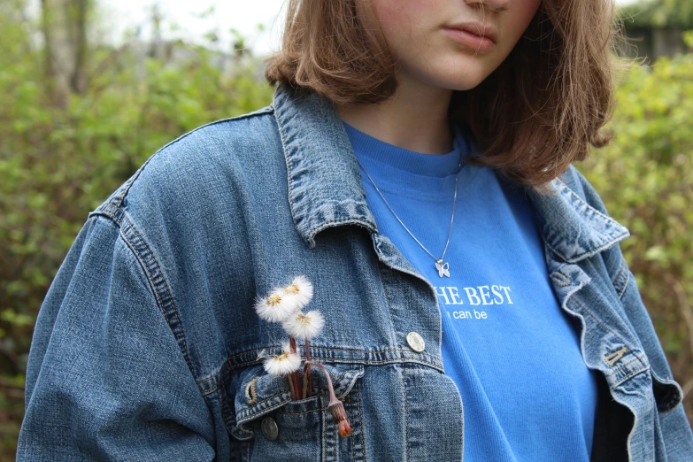 a woman wearing a blue shirt and denim jacket, by Eleanor Best, trending on pexels, dandelion, wearing jewellery, wearing a t-shirt, environmental shot