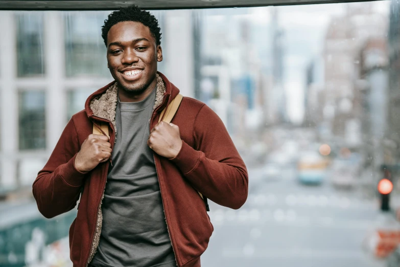 a man in a red jacket standing on a city street, by Carey Morris, pexels contest winner, brown skin man with a giant grin, wearing a grey hooded sweatshirt, avatar image, a man wearing a backpack