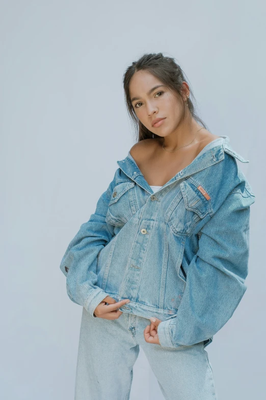 a woman wearing a denim jacket and jeans, an album cover, by Robbie Trevino, wearing an oversized hoodie, mai anh tran, on a pale background, loosely cropped