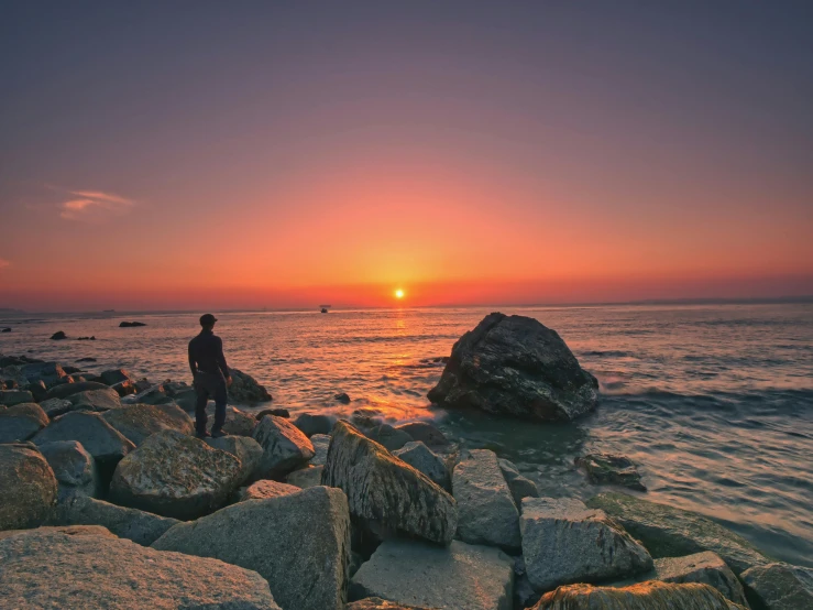 a person standing on rocks near the ocean at sunset, pexels contest winner, sunset + hdri, sunset warm spring, fisherman, realistic scene