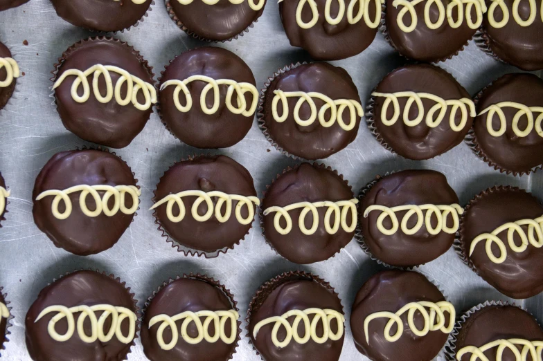 a tray of chocolate cupcakes with glasses on them, a portrait, pexels, hurufiyya, black and gold wires, thumbnail, glazed, cheesy