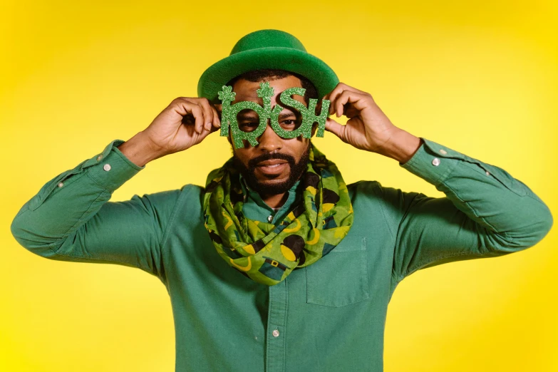 a man with a green hat and scarf covering his eyes, an album cover, inspired by Ras Akyem, trending on unsplash, funk art, four leaf clover, with nerdy! glasses! and goatee, donald glover, green and yellow