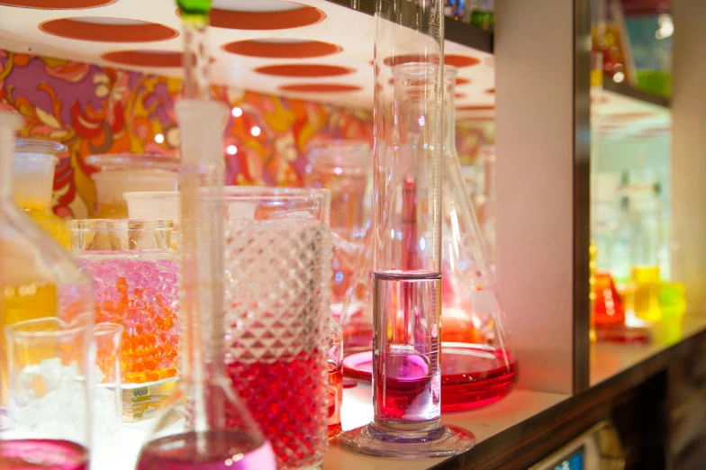 a shelf filled with lots of different colored liquids, by Anna Findlay, pexels, pink and orange neon lights, beaker, inside in a glass box, candy hospital room