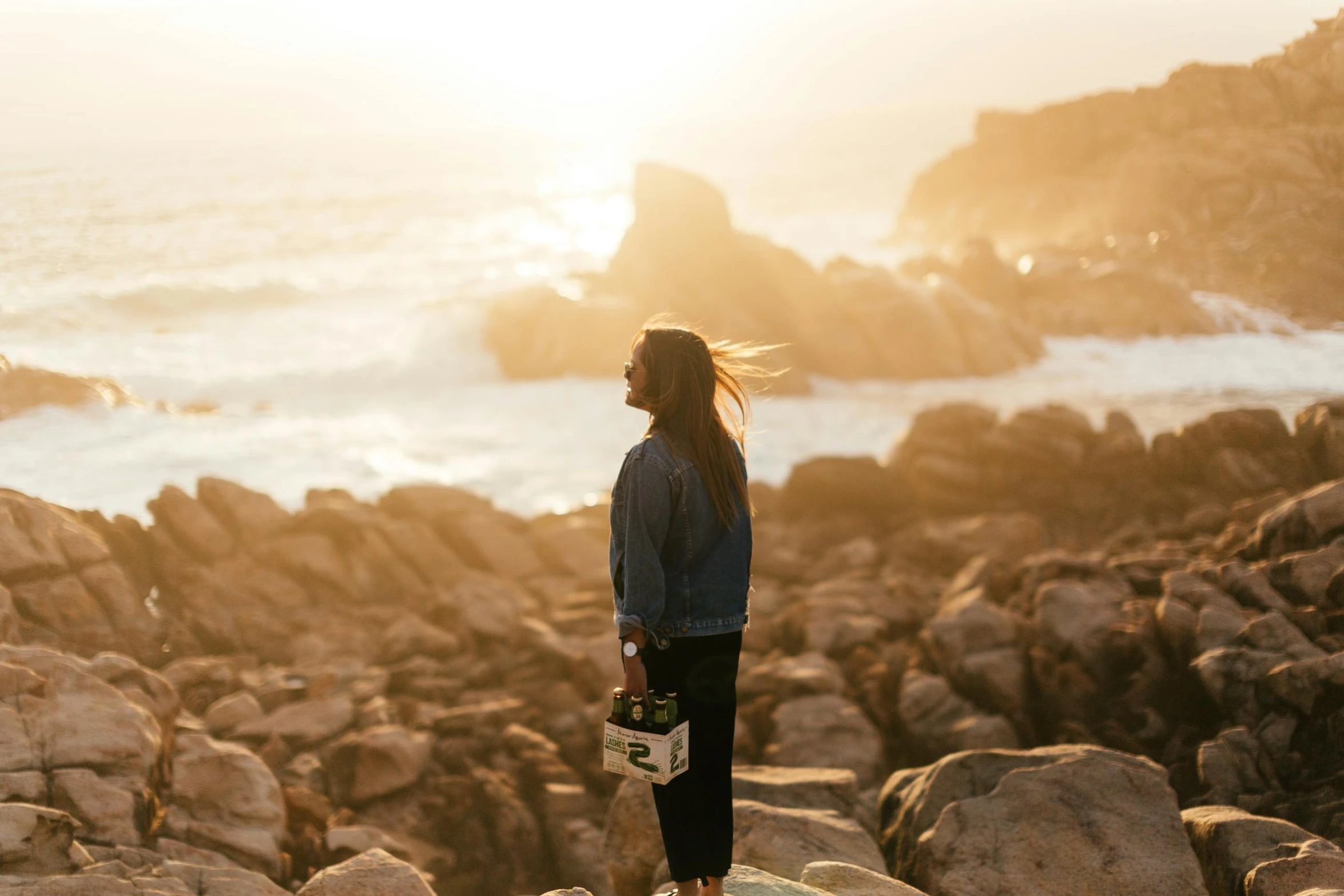 a woman standing on top of a rock next to the ocean, happening, profile image, golden hour photograph, conde nast traveler photo