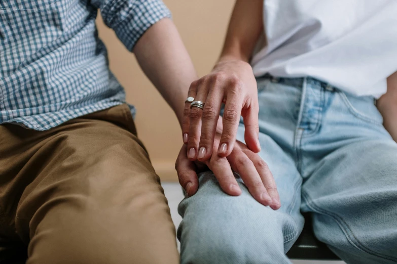 a close up of two people holding hands, trending on pexels, sitting on an armchair, her hand is on her waist, wearing casual clothing, colour photograph