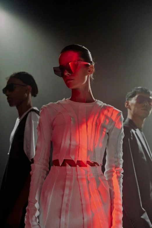 a group of people standing next to each other on a stage, a digital rendering, inspired by Tadashi Nakayama, trending on unsplash, bauhaus, fashion model in sunglasses, dramatic lighting !n-9, coated pleats, crimson led